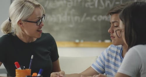 Teacher Explains Lesson to Two Teens in Classroom