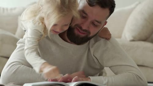Smiling Father Reading Book with Child at Home