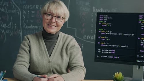 Porträt einer selbstbewussten Online-Schullehrerin, die mit Computer und Tafel im Klassenzimmer sitzt