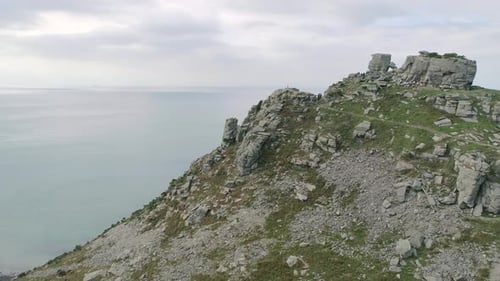 Forward tracking aerial towards the rocky outcrop on the cliffs of Exmoor, known as the Valley of ro