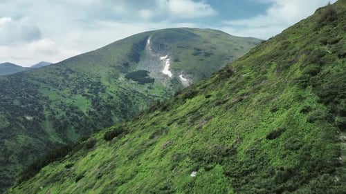 Bird-eye Wiev of a Rocky Grassy Mountain Range with a Trees and Hiking Trails on It.