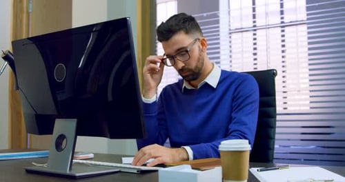 Executive sitting on desk in office