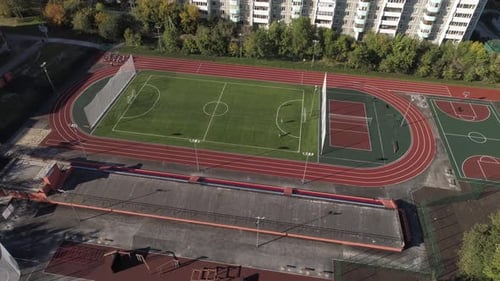 People play sports at the stadium in the yard in the city. Aerial 11