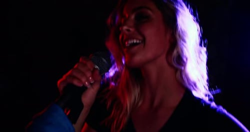 Woman Sings into Microphone with Stage Lighting