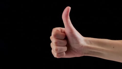 Close Up of Woman's Hand Showing Thumb Up Sign Isolated on a Black Background