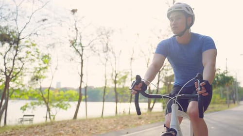 Asiatischer junger aktiver Sport Mann fährt Fahrrad für Gesundheit im öffentlichen Park.