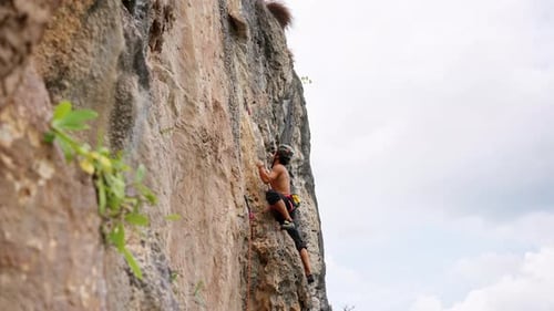 4K Junger asiatischer Mann klettert im Sommerurlaub auf Felsenberg auf tropischer Insel