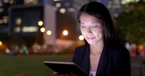 Woman Using Tablet at Night in the City