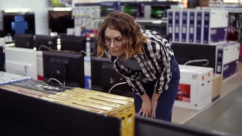 Smart Modern Female Customer Choosing Large TVsets at Electronics Store