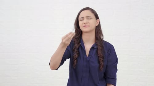 Woman Expressing Frustration Against White Brick Wall