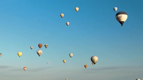 Hot air balloons fly over the mountainous landscape of Cappadocia, Turkey.