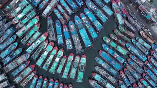 Aerial drone view of wooden boats leaning beside the pier. With noise cloud.