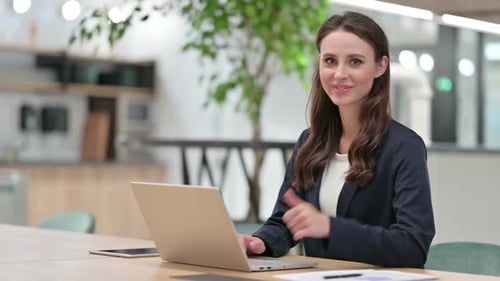 Woman Gives Thumbs Up While Working on Laptop