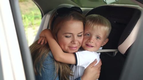 Woman and Child Embracing Tenderly in Car Backseat