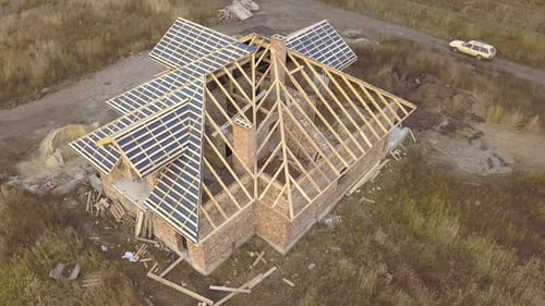 Aerial view of a house under construction works. Unfinished brick building with wooden frame