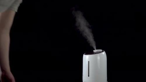 Un hombre encendió un humidificador ultrasónico sobre un fondo negro aislado