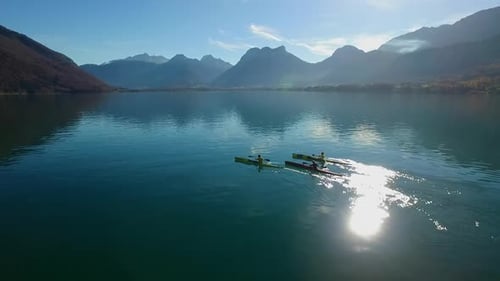Three kayakers paddle in a scenic mountain lake.