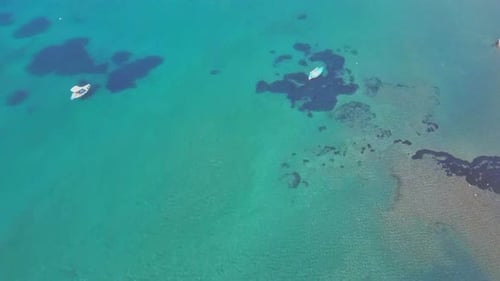 Vista aérea de cima para baixo de barcos de passageiros em águas rasas da costa oceânica. Beira-mar azul-turquesa e azul.