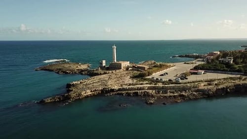 Drone flyby of a white lighthouse at the Mediterranean coastline of Sicily, Italy