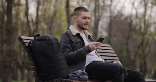 Slow Motion Man Use Smartphone Sitting on Bench in the Park