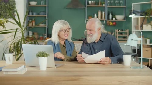 Senior Couple Working on Laptop with Documents Indoors
