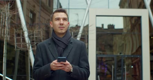 Portrait of Man Using Smartphone Near Modern Office Center. Chatting in Social Networks with His