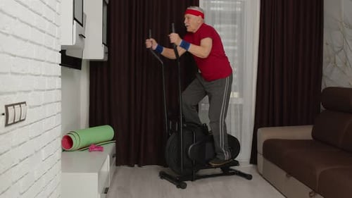 Senior Man Exercising on Elliptical Machine at Home