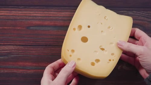 Flat lay. Large wedge of semi-soft part skim cheese on a rustic wood background.