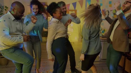 Câmera lenta de colegas masculinos e femininos dançando em um escritório decorado com taças de champanhe