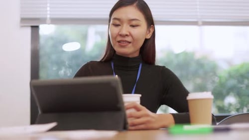 Woman Eating Noodles at Desk with Tablet