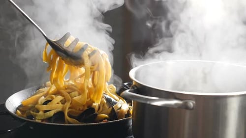 Steaming Pasta with Mussels Being Added to Pan