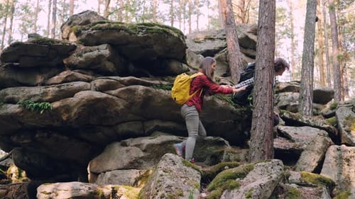Adventurous Young People Friends Are Trekking in Forest Climbing Up Huge Rocks Guy Is Helping Girl