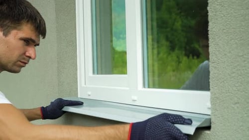 Trabalhador em luvas de proteção medindo moldura externa e tamanho do peitoril de metal da janela de PVC