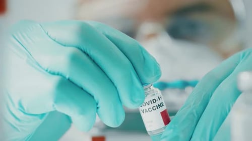 Scientist Examines a Vial with Coronavirus Vaccine