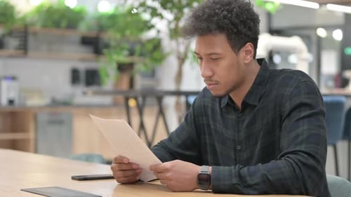 Man Reviews Documents in Modern Workplace Setting