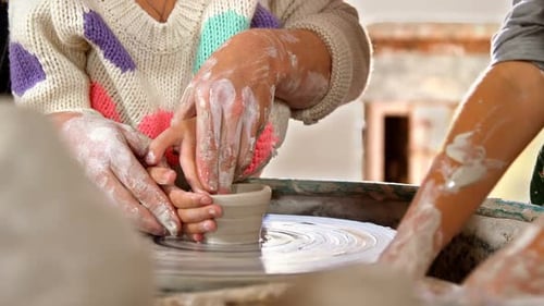 Child and Adult Making Pottery on Wheel Together