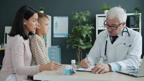Young Woman and Little Boy Discussing Health with Senior Doctor in Modern Clinic