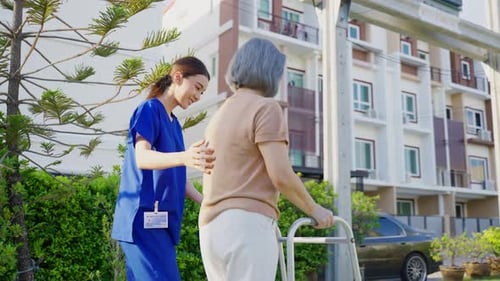 Caregiver Assists Senior Woman Using Walker Outdoors