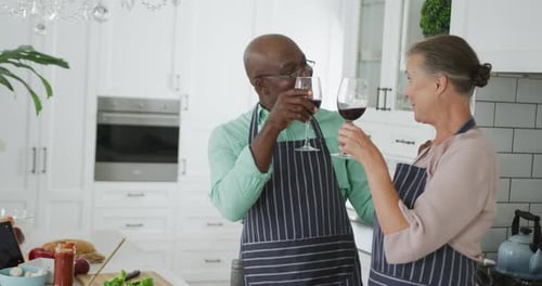 Senior Couple Toasts with Wine in Bright Kitchen