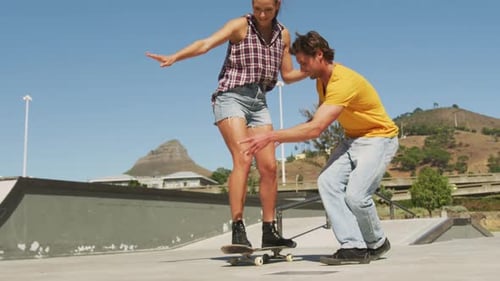 Woman Learning to Skateboard with Man's Support