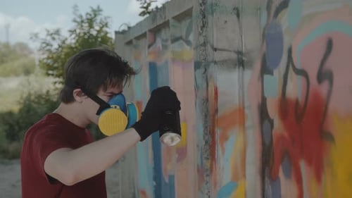 Graffiti Master with Respirator Painting on Street Wall