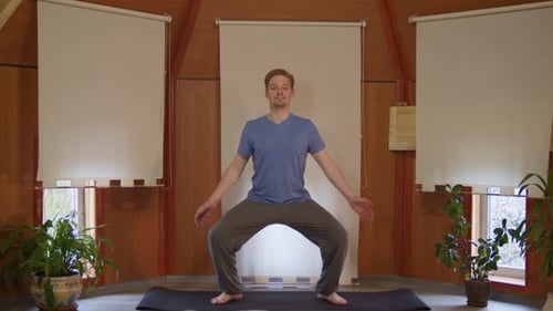 Young Man Practices Yoga in Indoor Studio