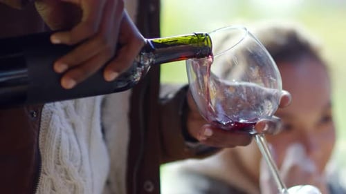 Mann gießt Wein ein