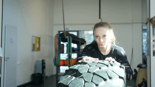 Kaukasische Sportlerin rollt im Fitnessstudio große Reifen
