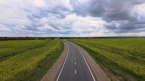 Aerial View of Intercity Road Between Green Agricultural Fields with Fast Driving Cars