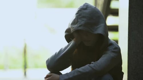 Melancholische Teenie-Frau im Hoodie berührt Gesicht mit Handfläche, leidet unter Depressionen