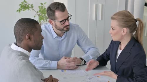 Serious Businesswoman Talking to Male Colleagues in Office