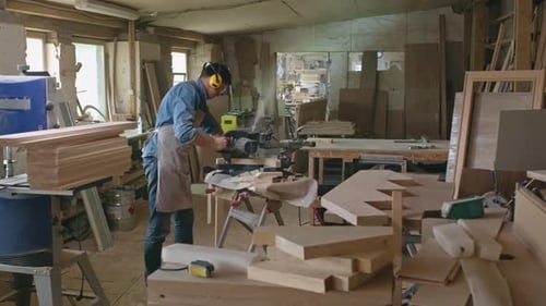Carpenter Sawing Wood Boards