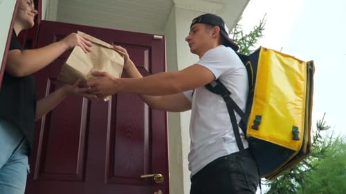 Side View Caucasian Delivery Boy Passing Order to Client at Door Walking Away