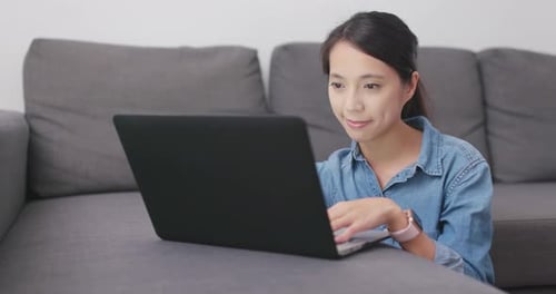 Woman Working on Laptop at Home on Couch